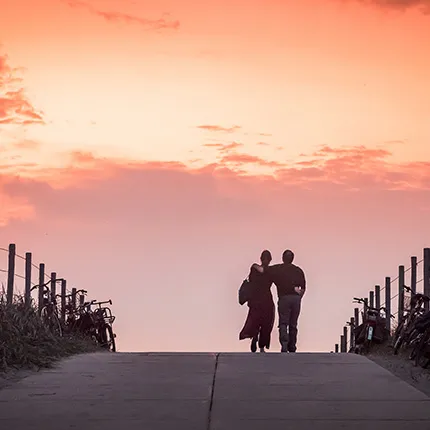 Couple walking in the dunes at sunset